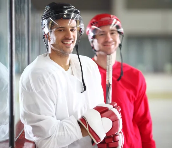 Zwei Eishockeyspieler in wei&szlig;em und rotem Oberteil l&auml;cheln in die Kamera