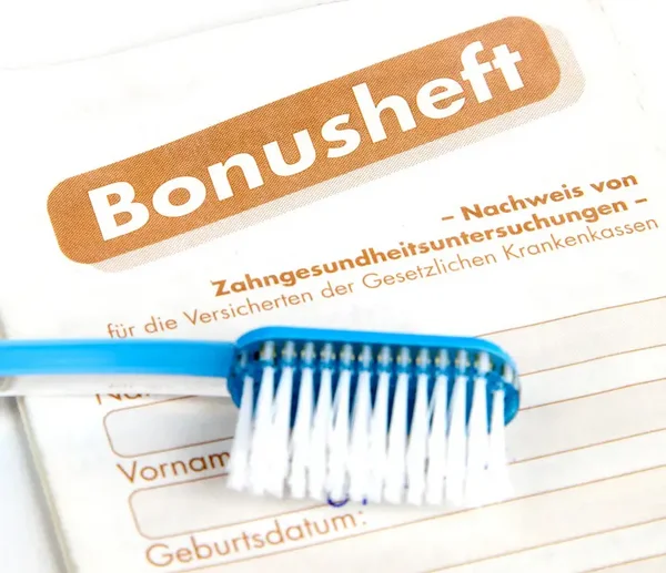 blaue Zahnbürste die auf einem Bonusheft liegt